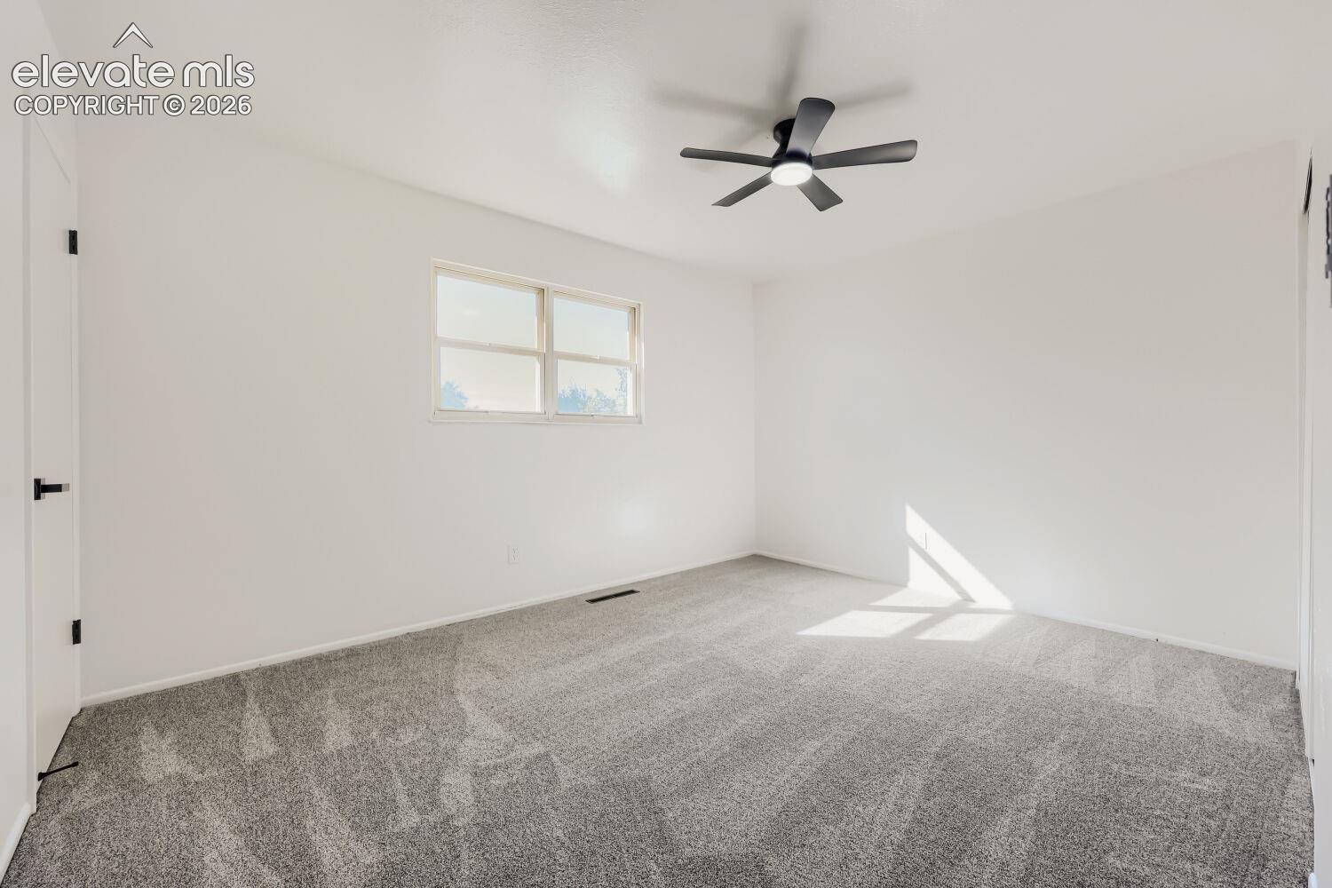 Window with natural light, neutral wall colors, textured carpeting, and a ceiling fan with integrated lighting