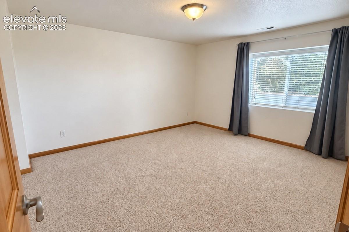 Carpeted room with a large window and a flush-mount ceiling light fixture