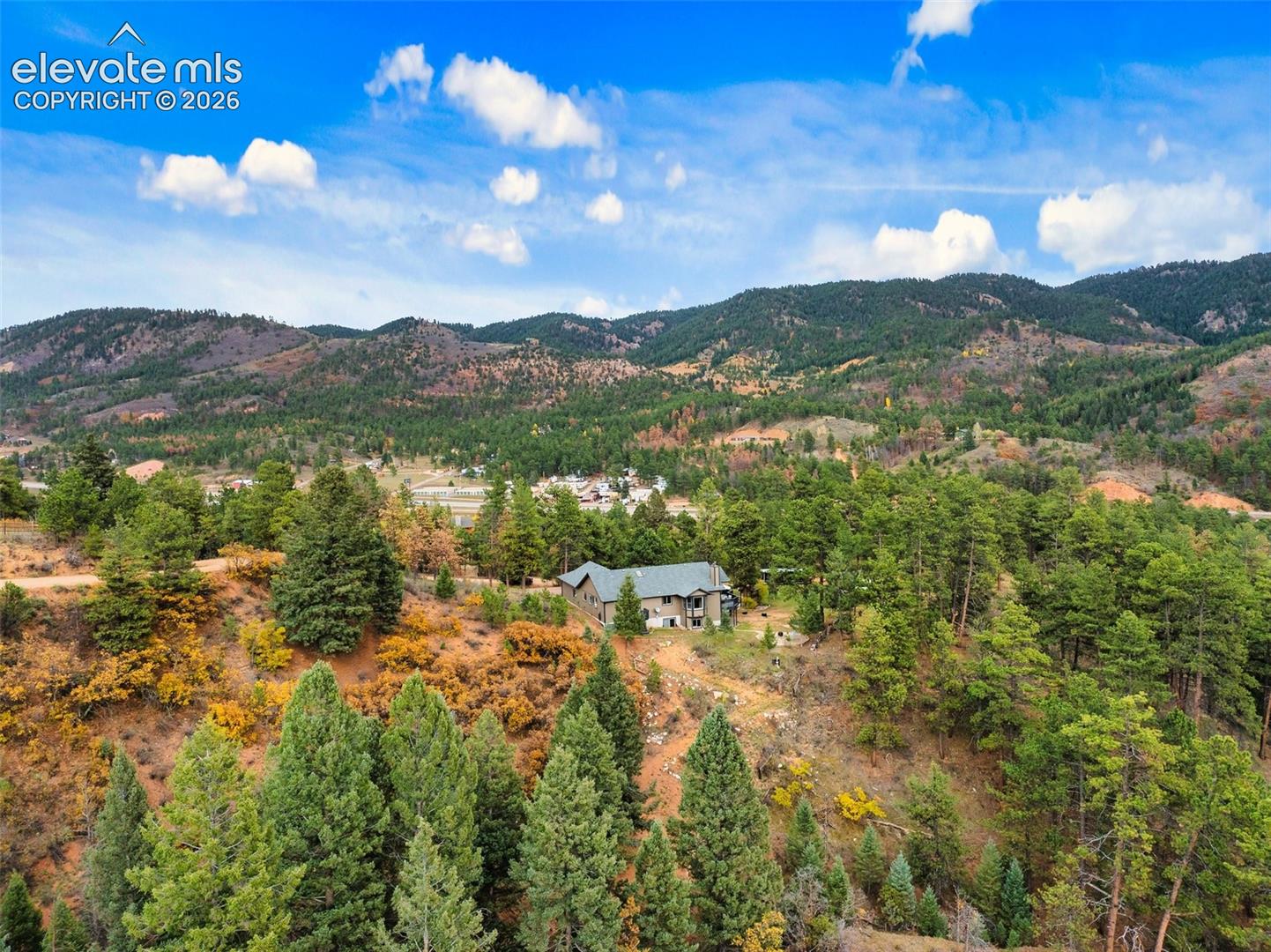 Multi-story residence nestled within a vast, treed landscape featuring mature evergreen foliage and expansive mountain terrain