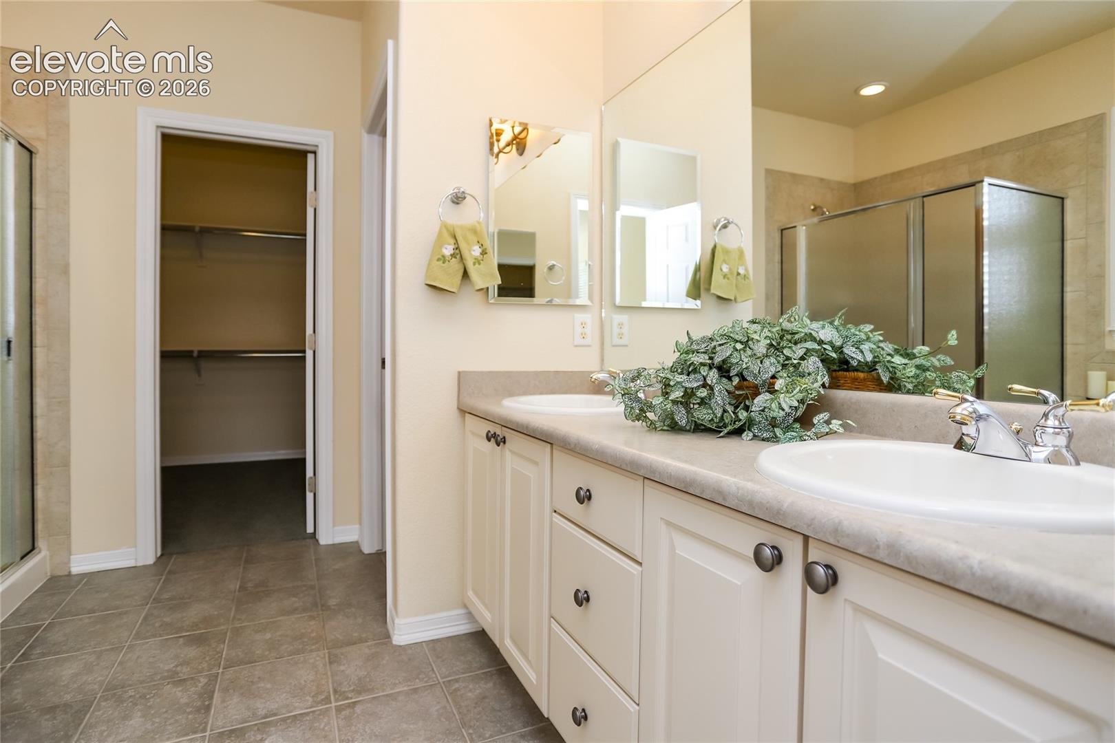 Primary bathroom features an extended vanity with dual sinks and tile flooring.