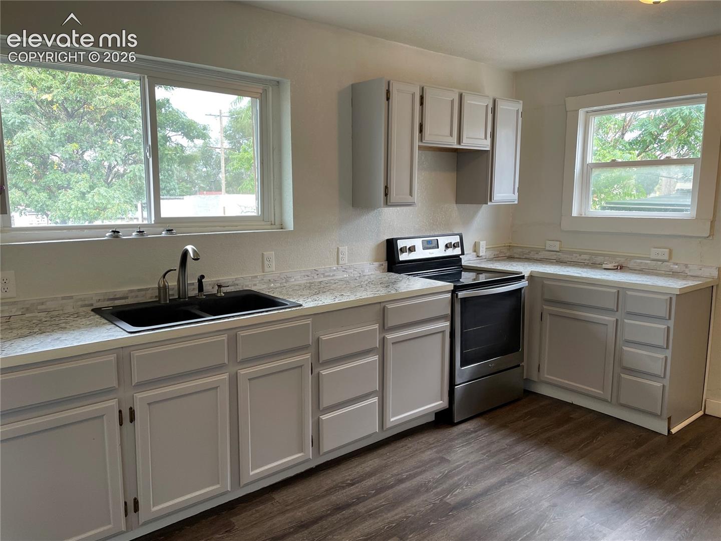 Kitchen featuring light grey cabinetry with brushed nickel hardware, white stone-look countertops, and a white subway tile backsplash