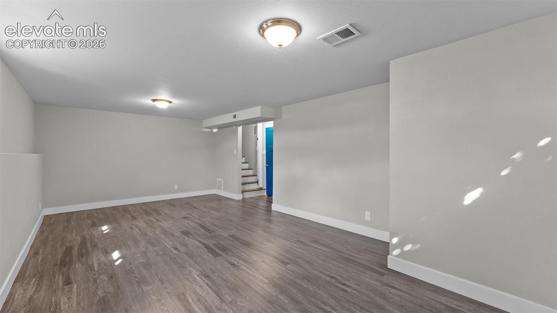 Spacious room featuring wood-finish flooring, light gray walls, and white trim