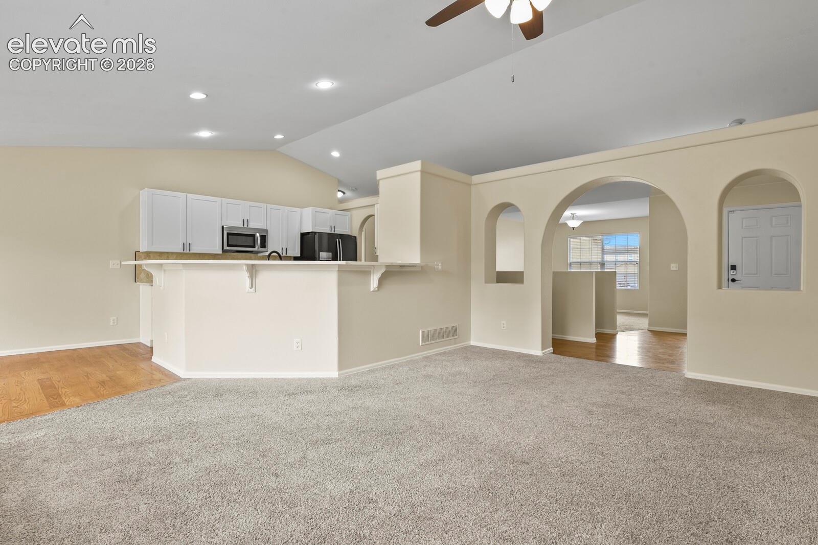 Spacious living area featuring vaulted ceilings, recessed lighting, and a neutral color palette