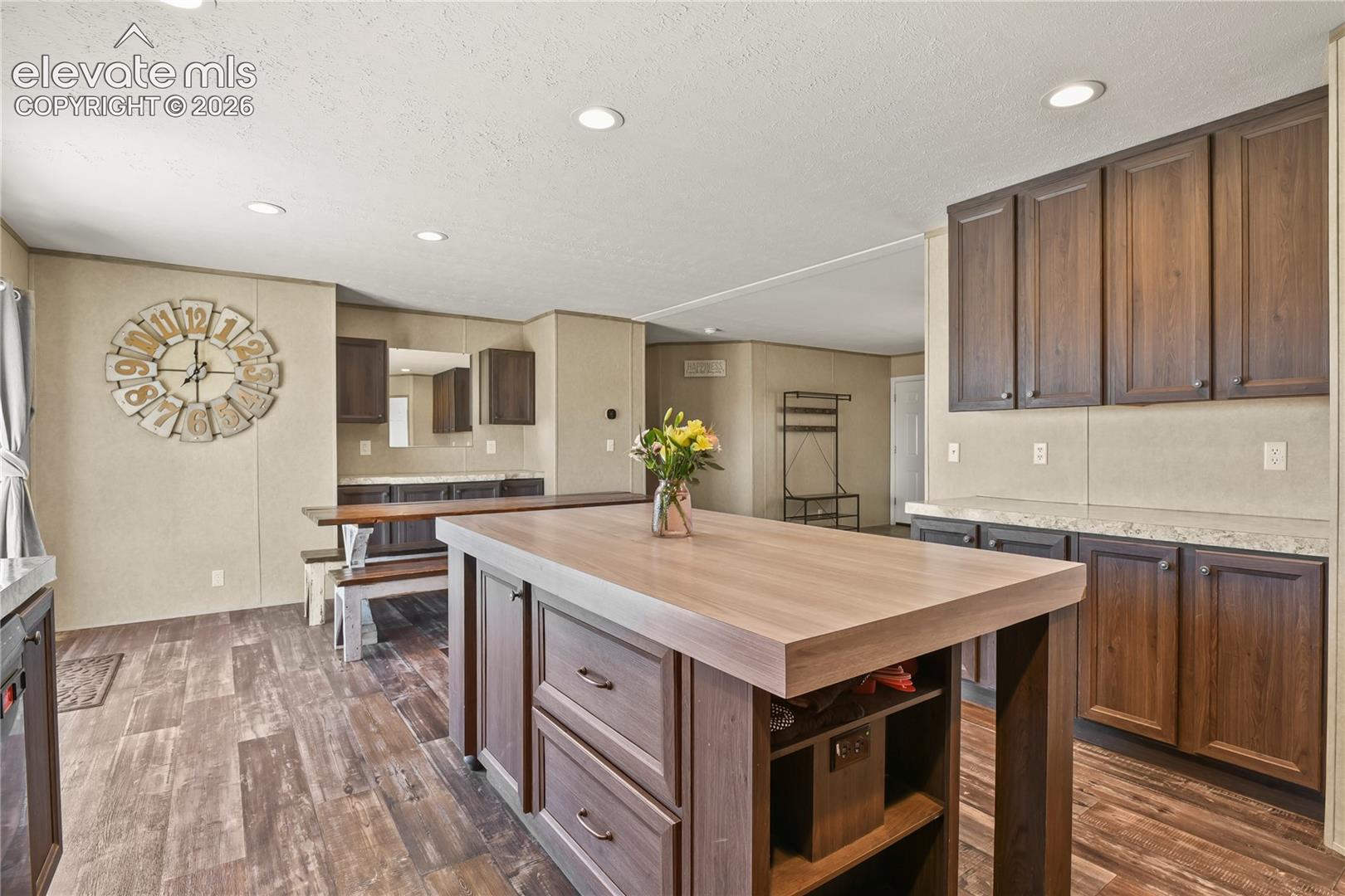 Kitchen featuring dark wood-finish cabinetry, central island with a wood-finish countertop, stone-finish countertops, recessed lighting, and wood-finish flooring