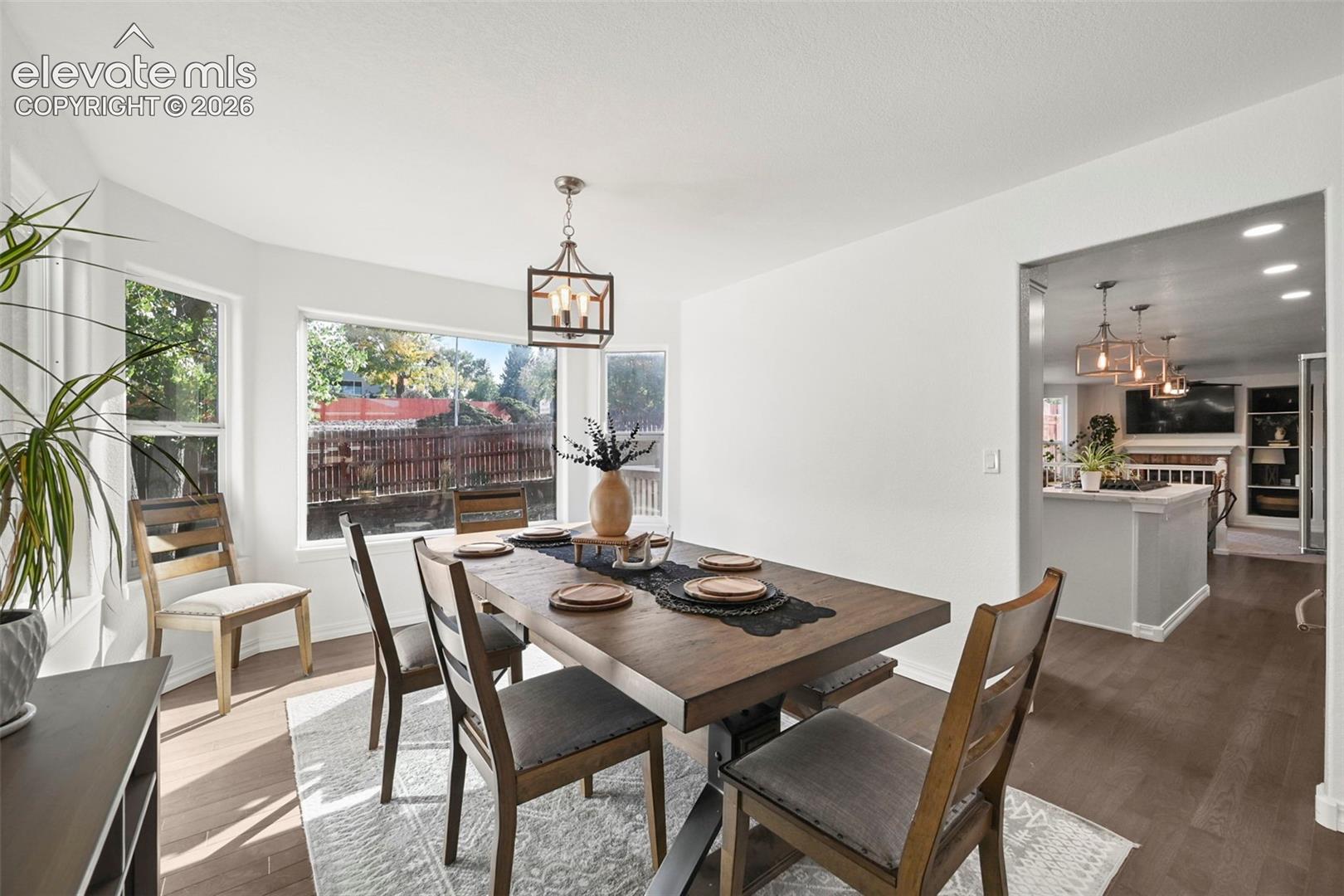 Recessed lighting, wood-finish flooring, bay windows, and a decorative pendant light fixture