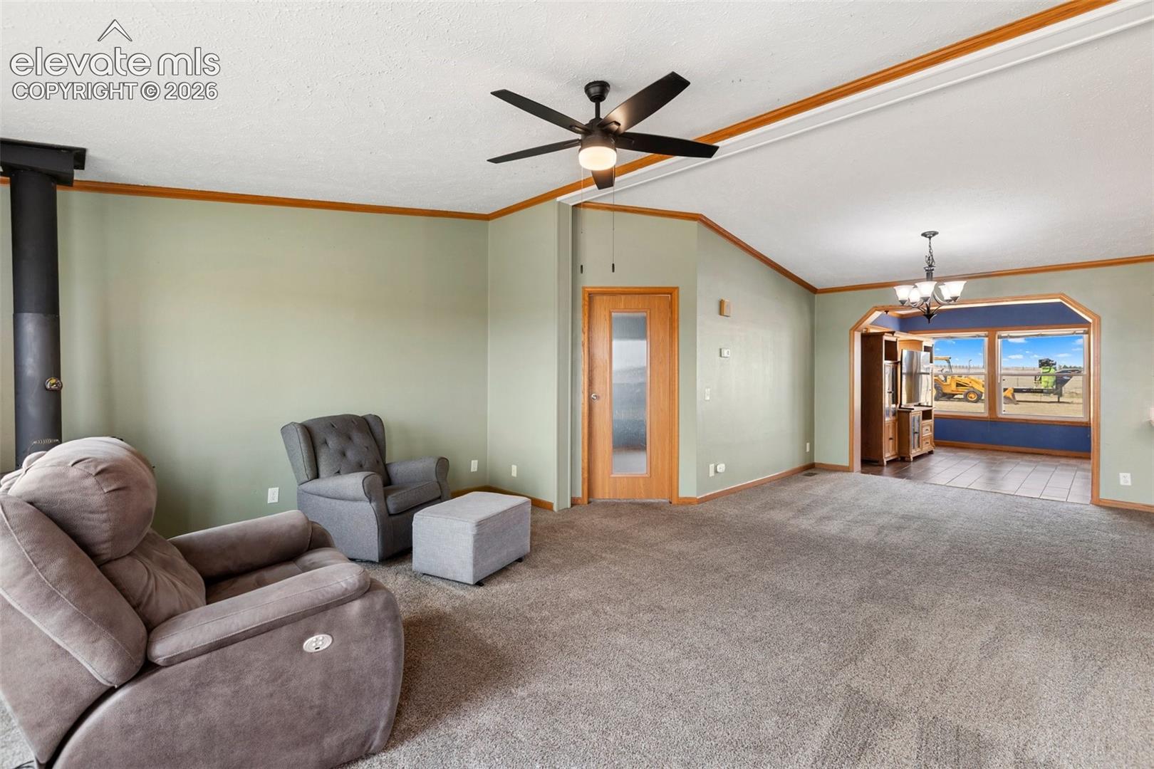 Spacious living area featuring neutral carpeting, light green walls, and a black ceiling fan with integrated lighting