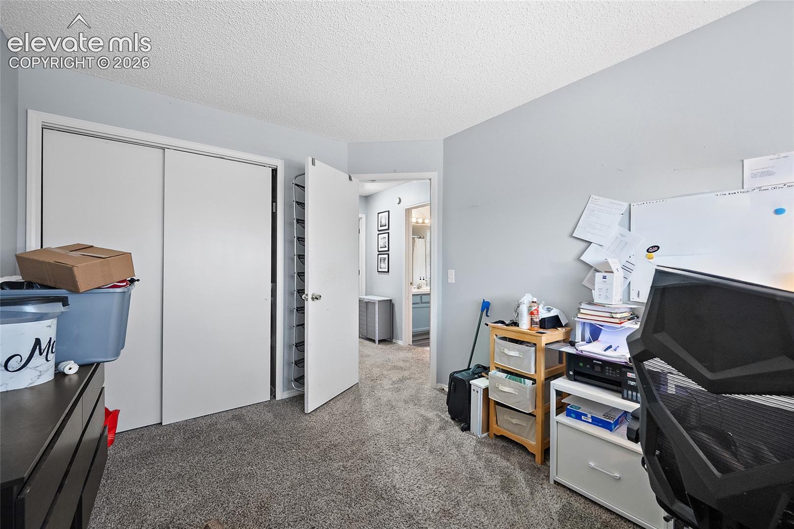 Room featuring gray wall paint, textured ceiling, light gray carpet, and a white bi-fold closet door