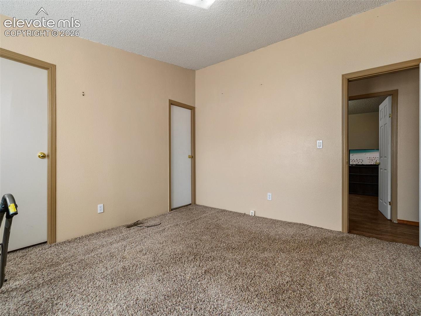Neutral wall finishes, textured ceilings, wall-to-wall carpeting, and interior passage doors with brass-finish hardware