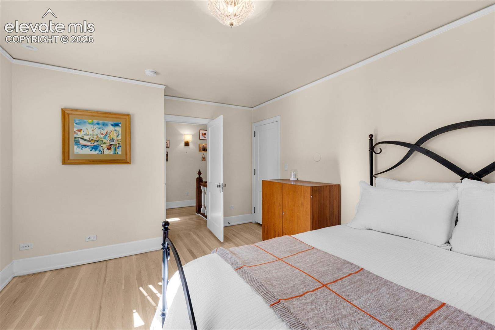 Light-filled room featuring wood-finish flooring, neutral wall paint, and a glass-shade flush mount ceiling fixture