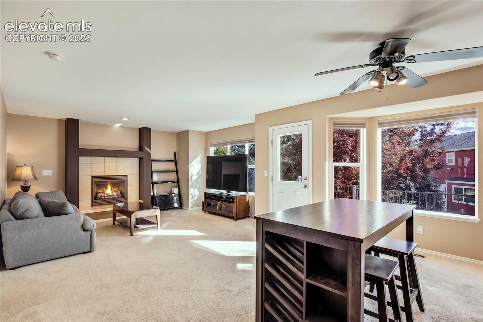 A wall of windows overlooks the mature landscaping, while the adjacent Great Room's gas fireplace creates a warm setting for gatherings.