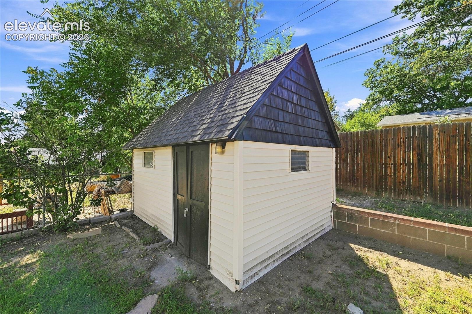 Outdoor storage shed featuring a gabled roof with dark shingles, horizontal siding, and a pair of dark-toned doors