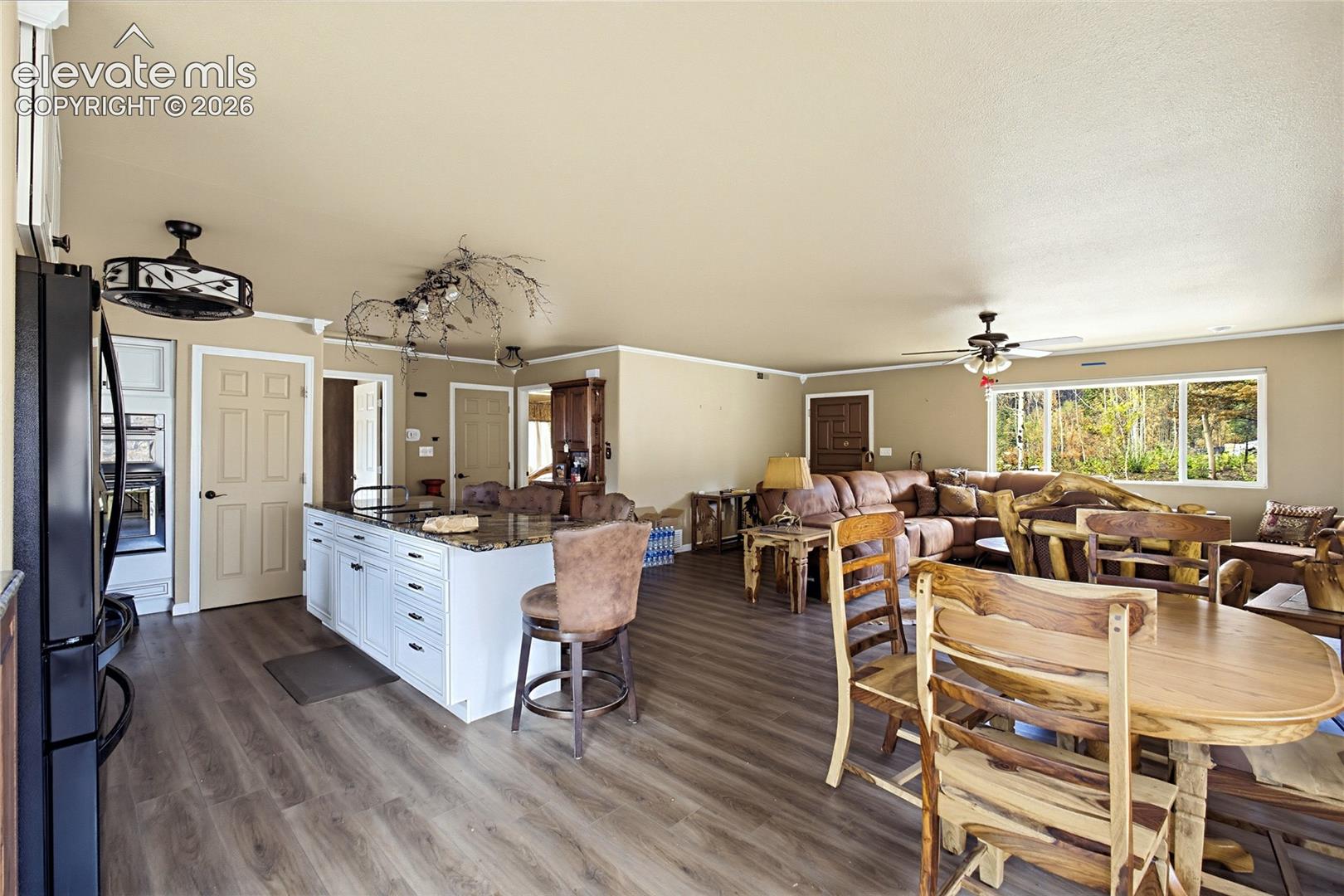 Kitchen featuring a central island with stone-finish countertops, white cabinetry, wood-finish flooring, and dual ceiling-mounted fans