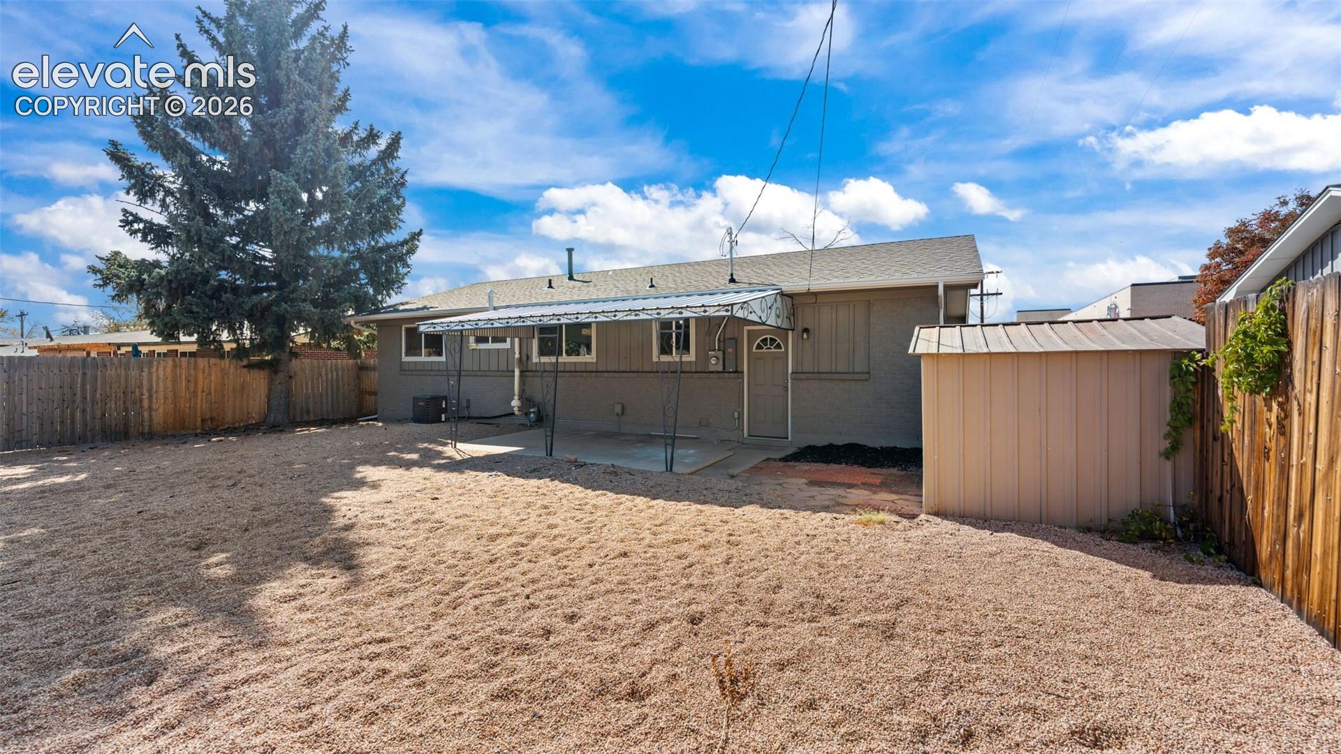 Expansive backyard with gravel landscaping, private wood fencing, and a covered patio area