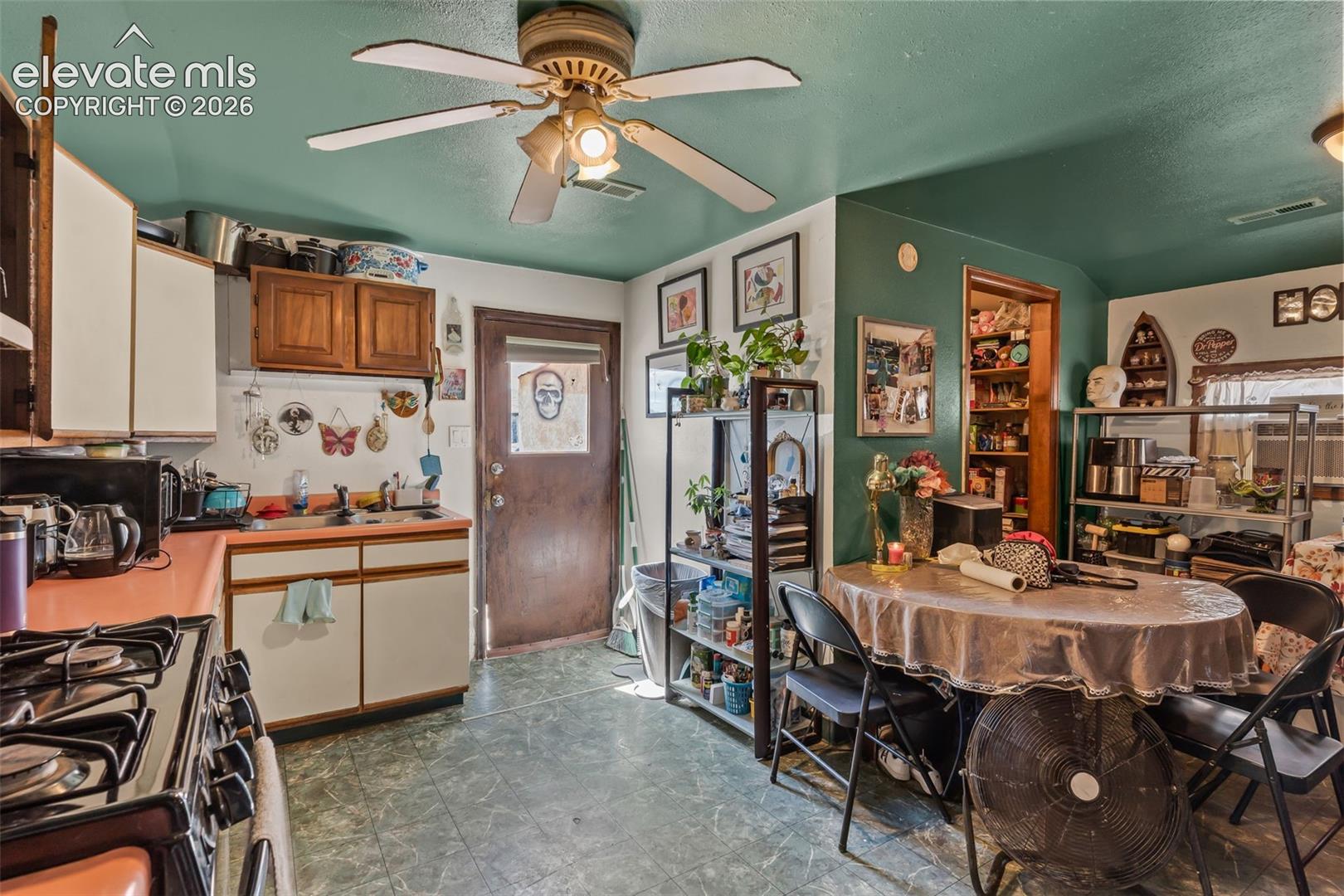 Functional kitchen featuring a gas range, dual-basin sink, and a ceiling fan with integrated lighting