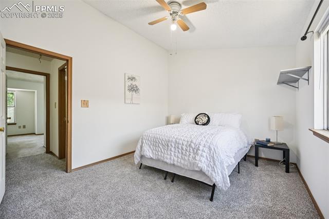 Carpeted bedroom featuring ceiling fan and a textured ceiling