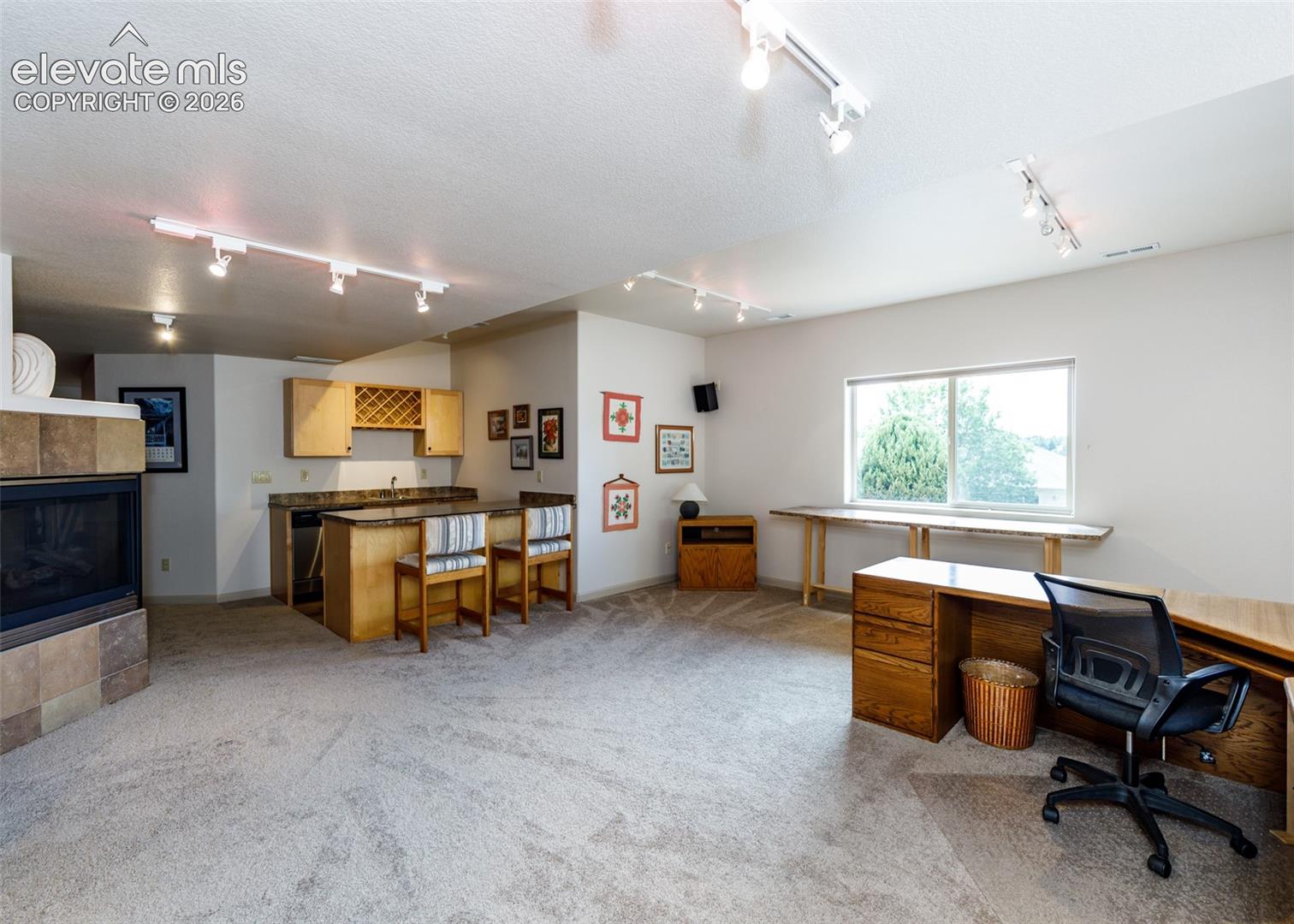 Bright lower level offers 3 sided built-in gas fireplace with stone surround, wet bar, tack lighting and walkout.