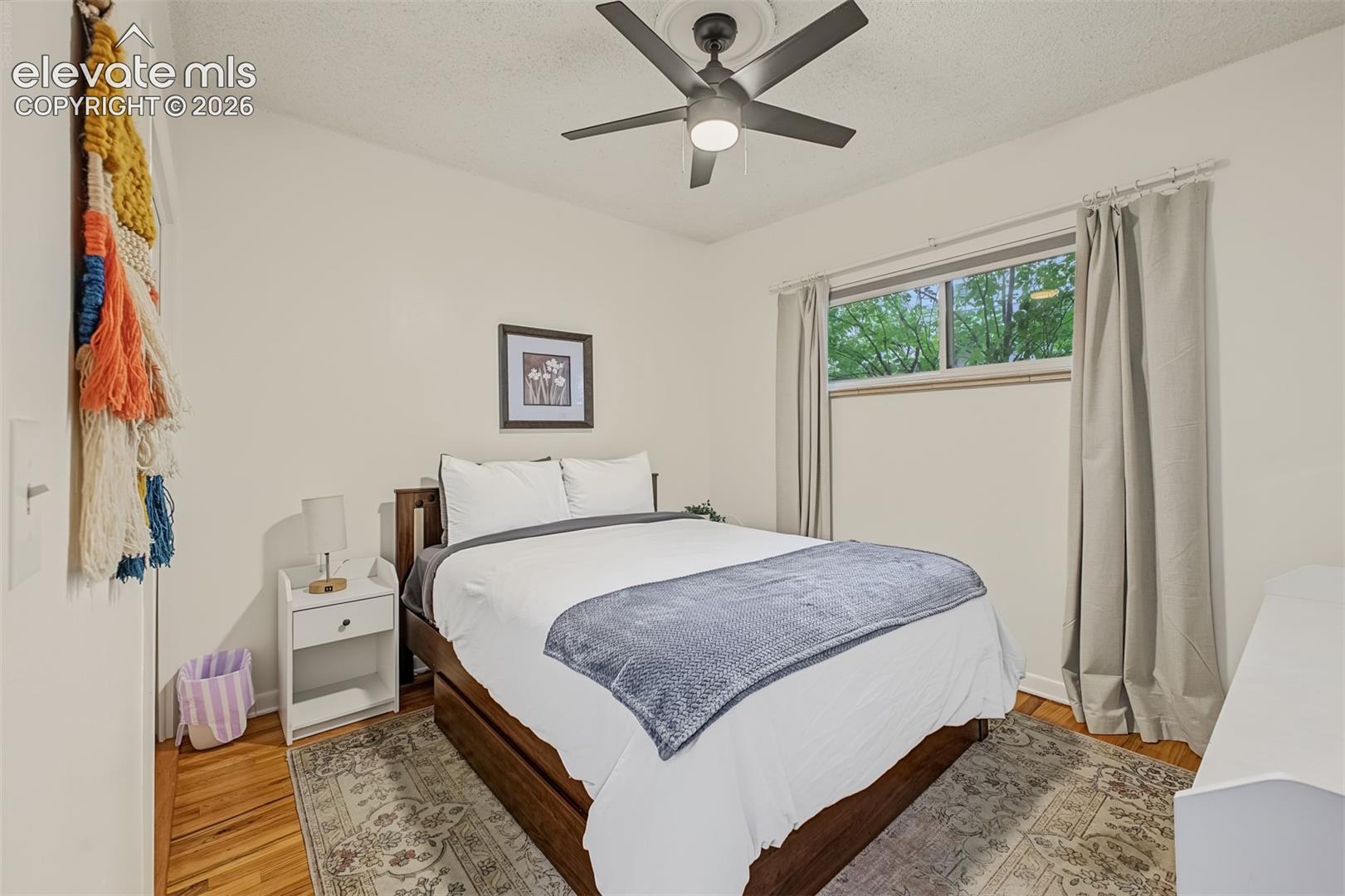 Room featuring wood-finish flooring, a ceiling fan with a centered medallion, and a horizontal sliding window