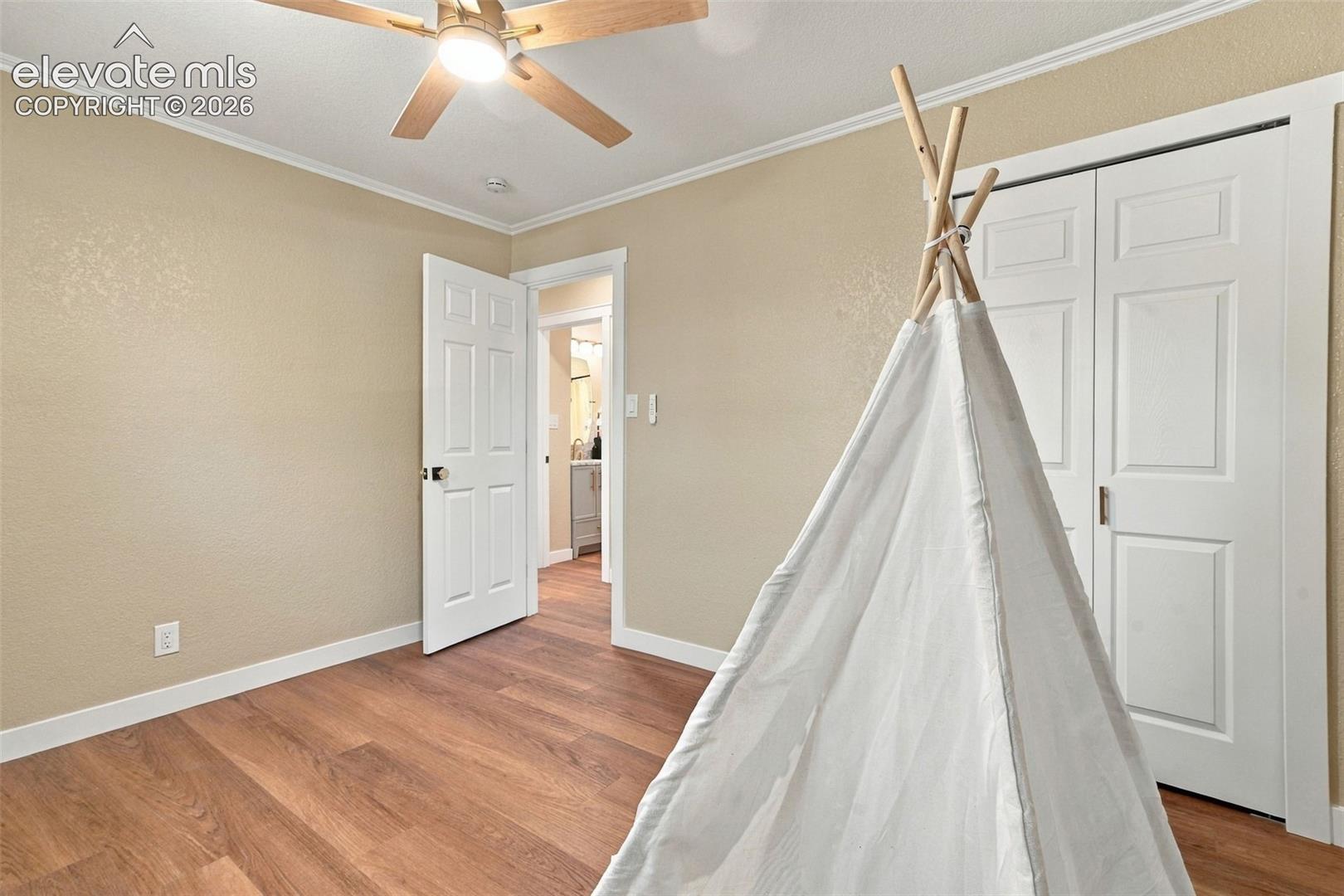 Wood-finish flooring, ceiling fan with integrated lighting, and dual-panel closet doors