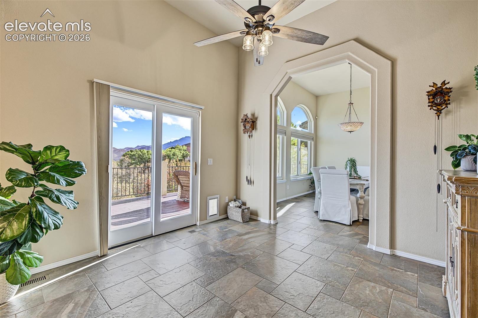 Additional dining or breakfast nook space featuring tile flooring, a ceiling fan, and sliding glass doors opening to the rear deck with mountain views. Arched entry leads to the formal dining area.