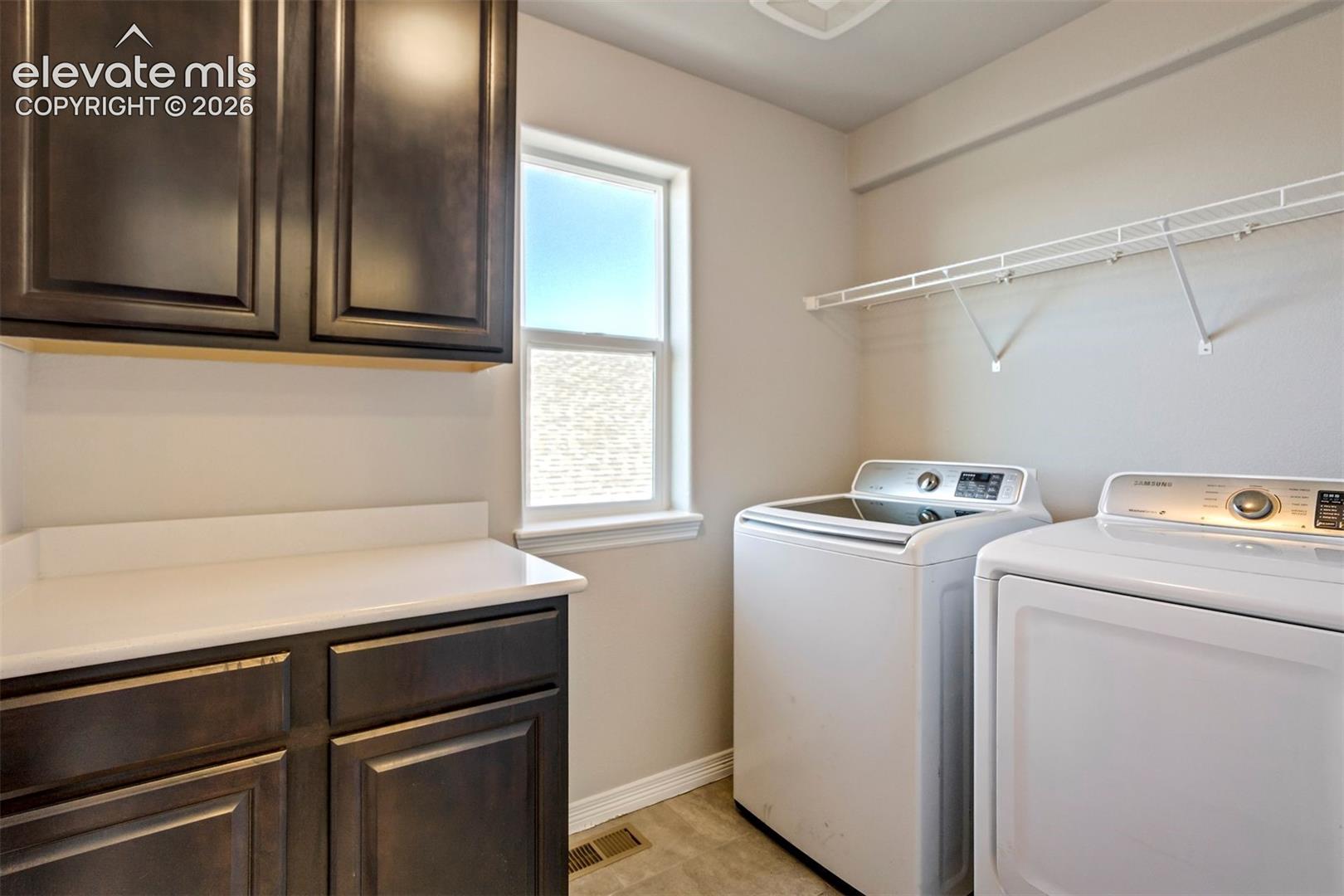 Utility room featuring dark wood-finish cabinetry, a white countertop, a window with natural light, and wire shelving