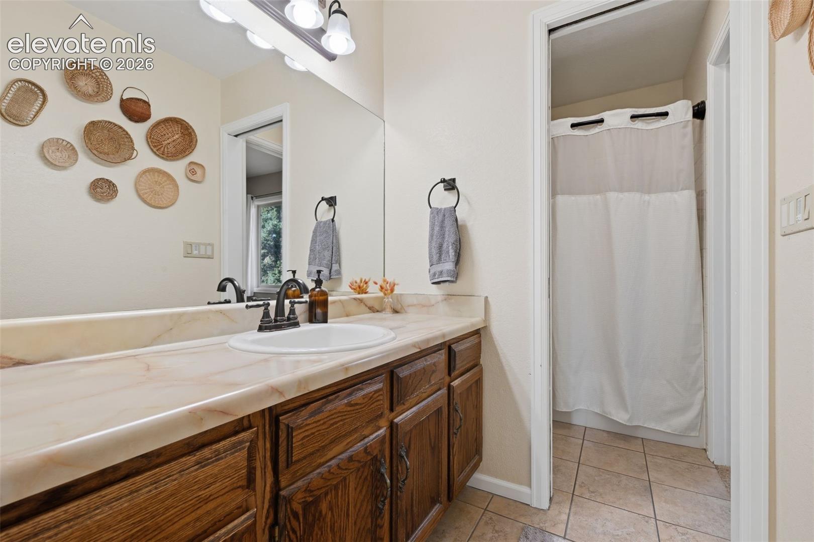 Bathroom vanity featuring a single basin, bronze-finish faucet, and substantial mirror