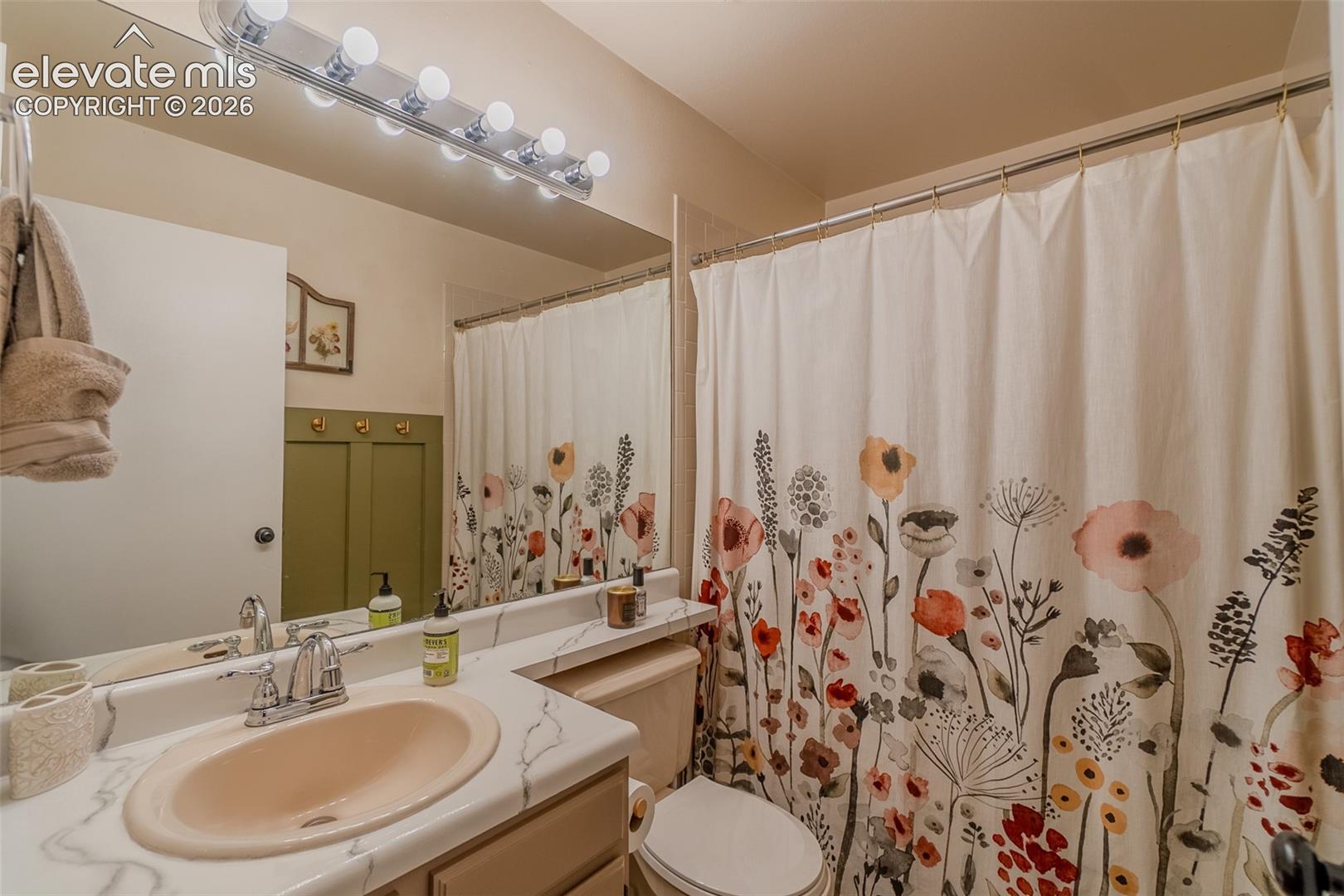 Vanity with integrated sink and chrome faucet, large wall mirror, and overhead vanity lighting