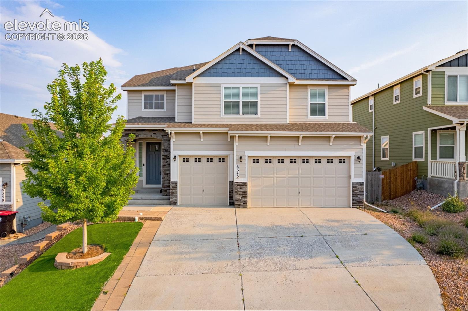 Two-story exterior with a two-car garage, stone accents, and a covered entry