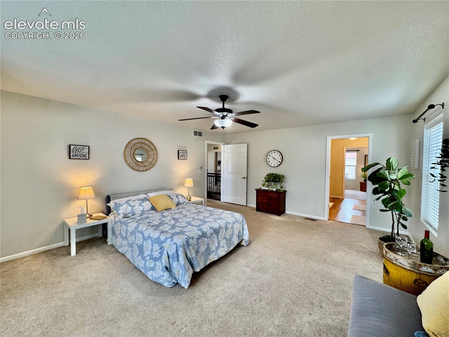 Spacious carpeted room featuring a ceiling fan with integrated lighting, two white panel doors, and a window with blinds
