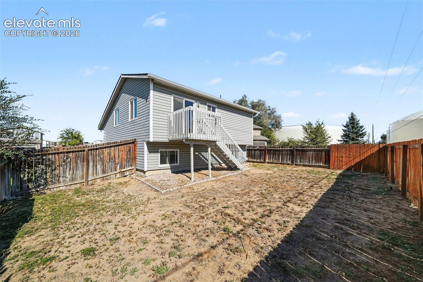 Exterior siding, elevated wood deck with stairs, and perimeter wood fencing
