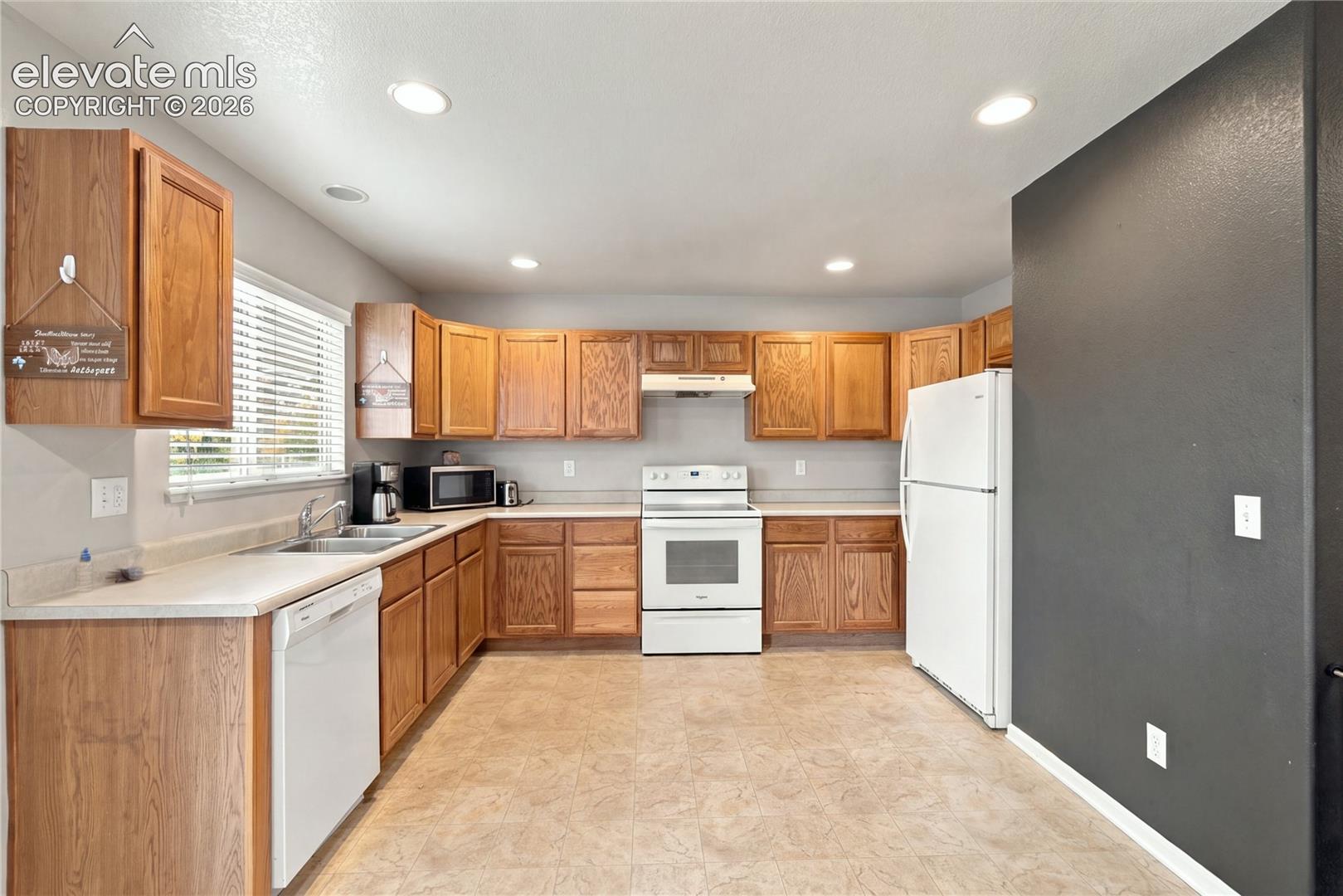 Kitchen featuring wood cabinetry, recessed lighting, and white appliances including a range, dishwasher, and refrigerator