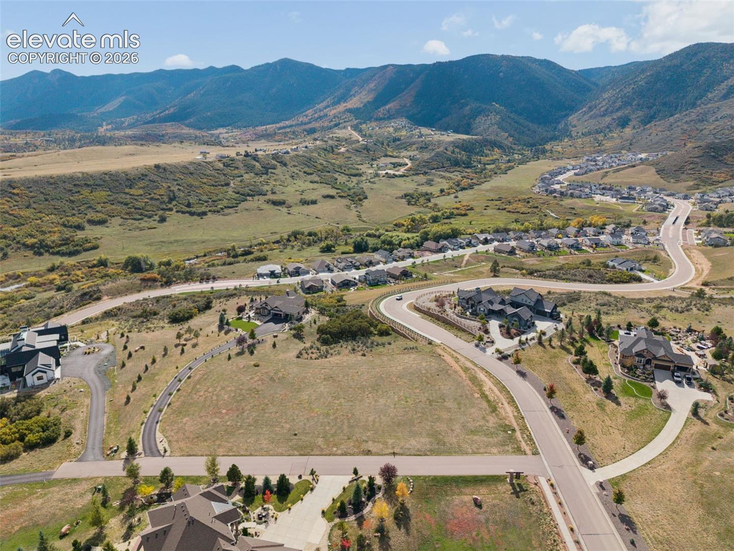 Aerial perspective of a multi-acre parcel featuring expansive mountain range surroundings, natural topography, and paved street access