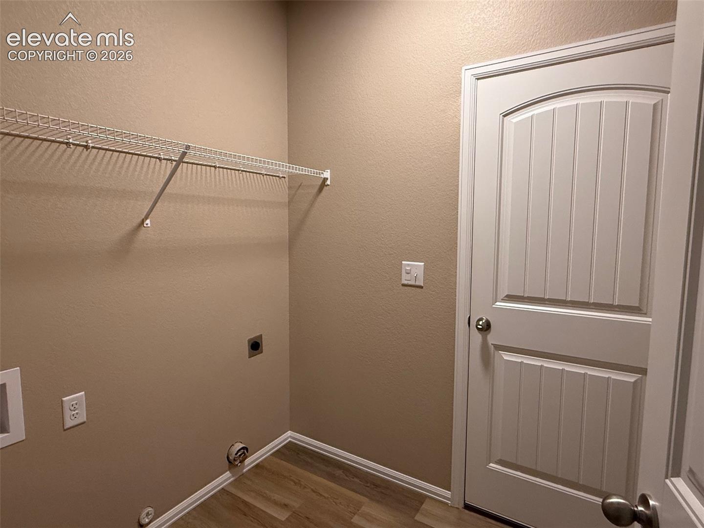 Wood-finish flooring, white wire shelving, paneled interior door, and white trim