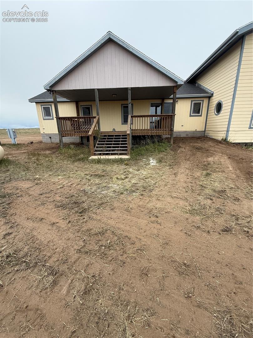 Rear exterior with a covered porch, wood-tone decking, and a sloped roofline