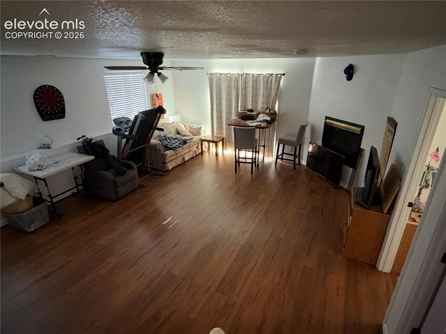 Living area featuring wood-finish flooring, a fireplace with a black surround, and a ceiling fan