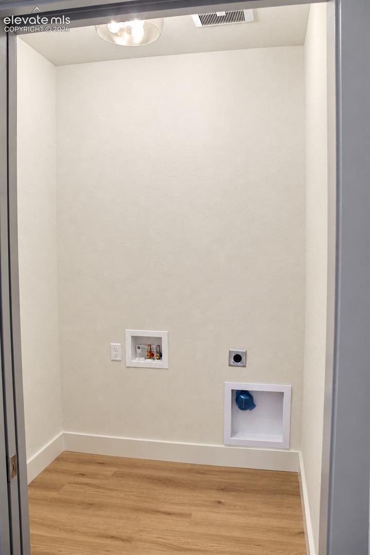Dedicated utility space featuring wood-finish flooring, white baseboards, and a ceiling-mounted light fixture