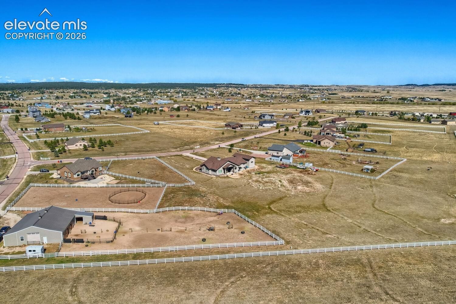 Expansive property featuring a large outbuilding, white fencing, and a circular riding arena