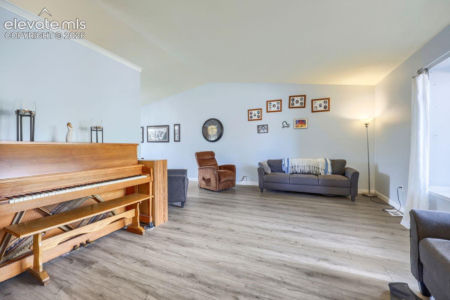Wood-finish flooring throughout, vaulted ceiling with crown molding, and light-toned wall paint