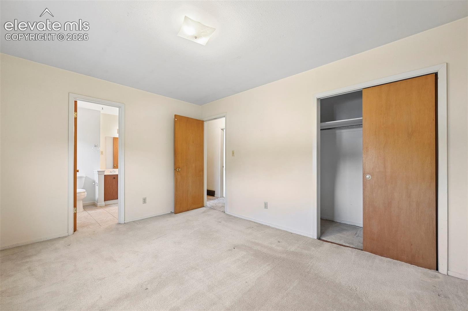 Primary bedroom with wood-finish sliding closet doors and attached bathroom 
