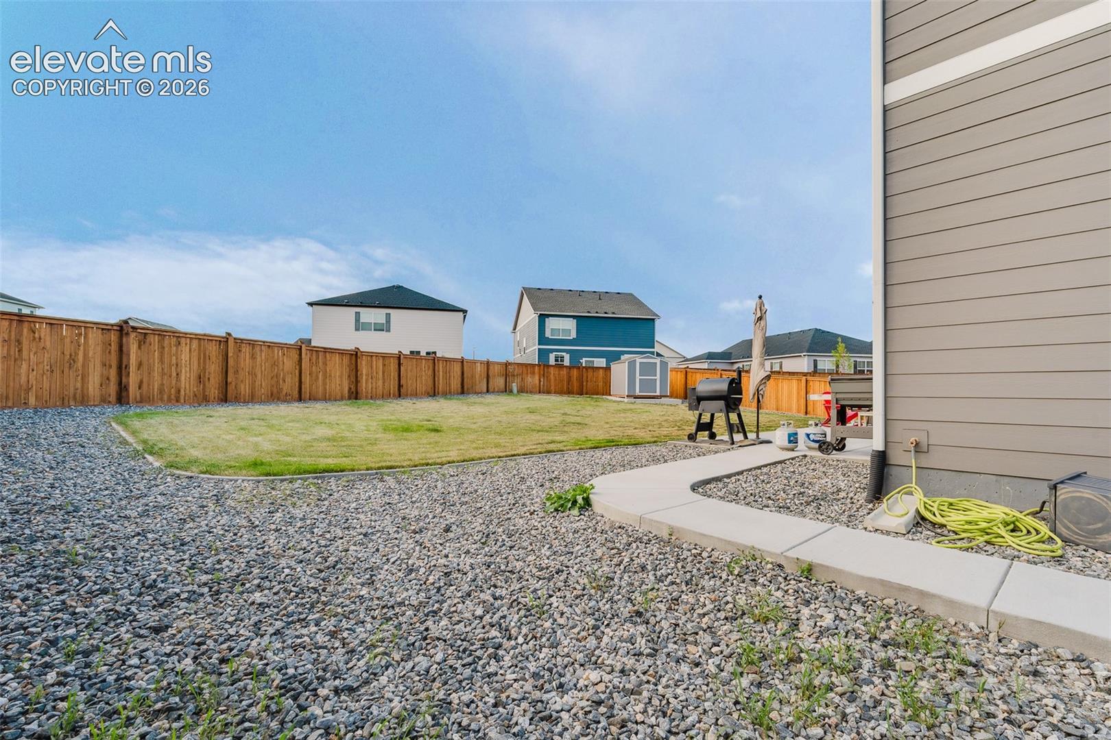 View of backyard and storage shed for tools and toys.