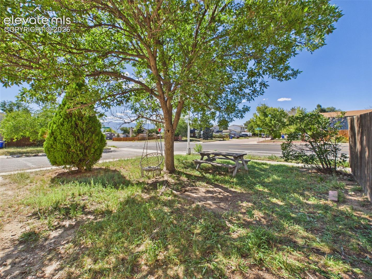Mature shade trees create a pleasant outdoor setting with a picnic table and additional space for seating or recreation.