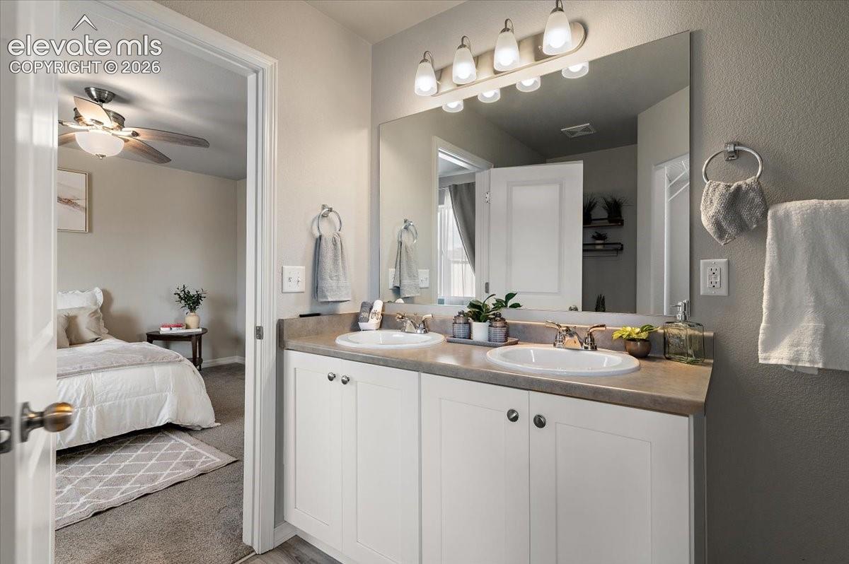 Dual vanity with white cabinetry, polished chrome fixtures, and a large mirror