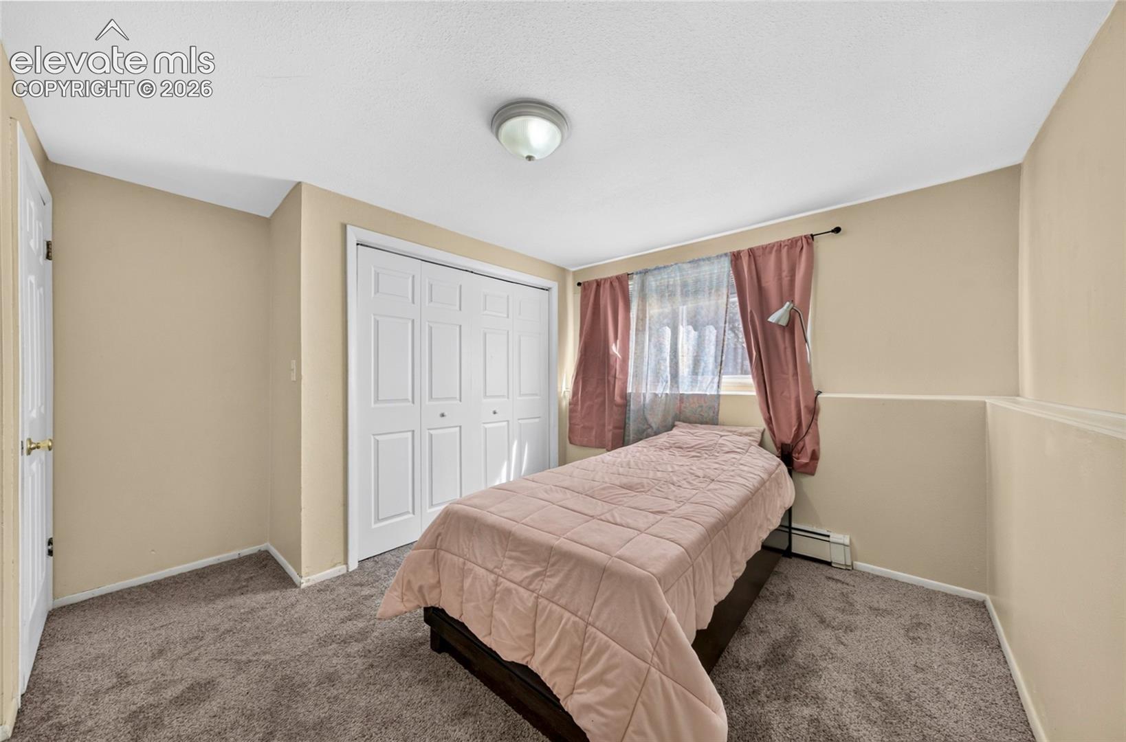 Interior room featuring wall-to-wall carpeting, a multi-panel sliding closet door, and a flush-mount ceiling light fixture