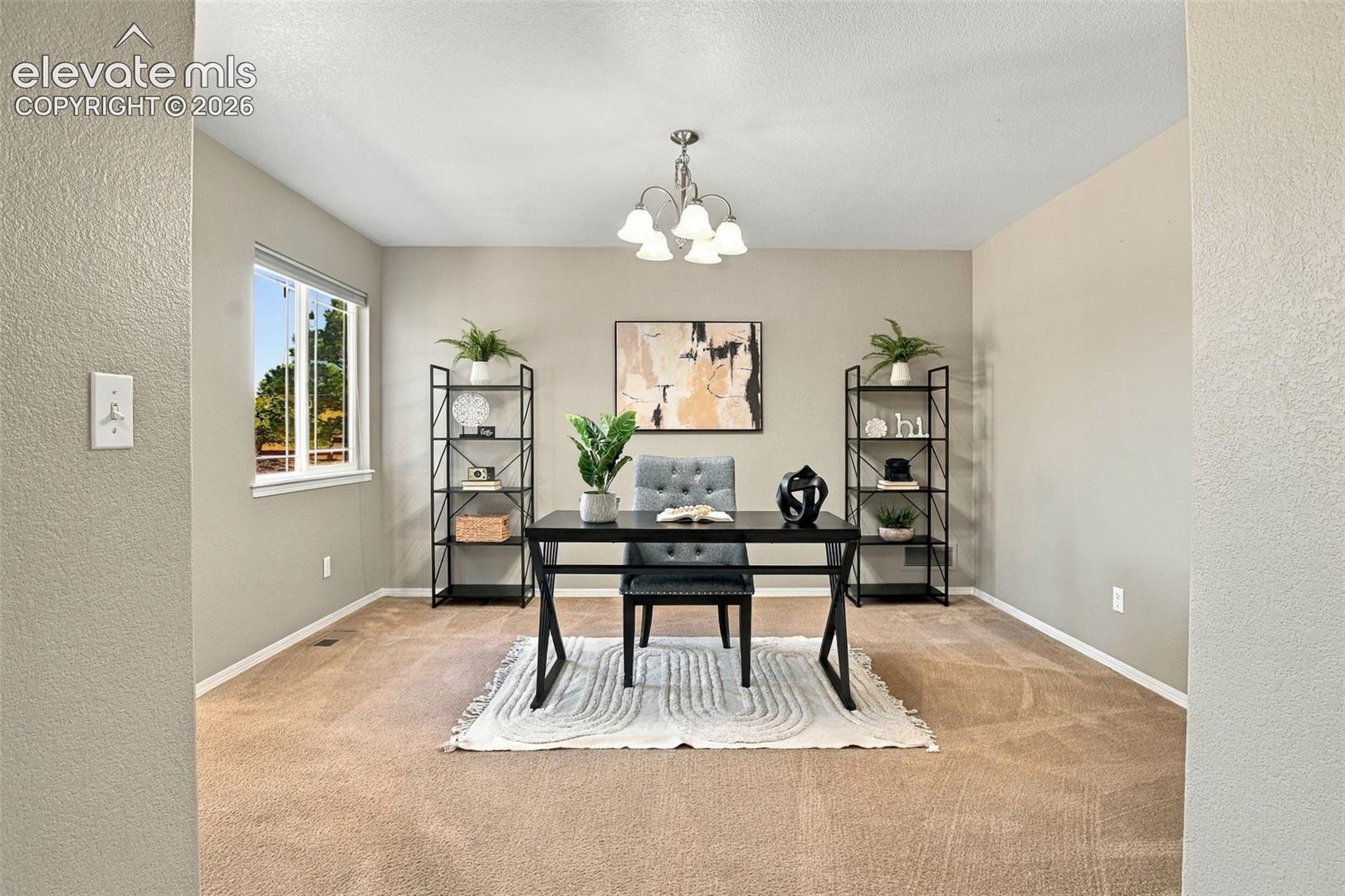 Recessed lighting and a multi-light chandelier illuminate this space featuring a window with white trim