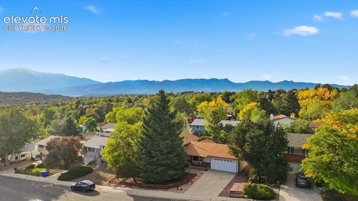 Mountain backdrop, tree-lined neighborhood, residential street, concrete driveway, attached garage