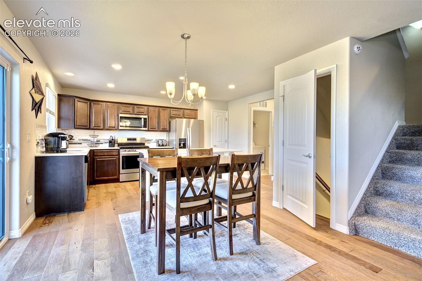 Kitchen featuring dark wood-finish cabinetry, stainless steel appliances, recessed lighting, wood-finish flooring, and a multi-arm chandelier
