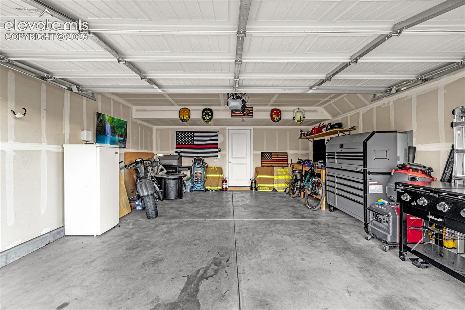 Spacious two-car garage with concrete flooring, finished walls, and white paneled overhead doors