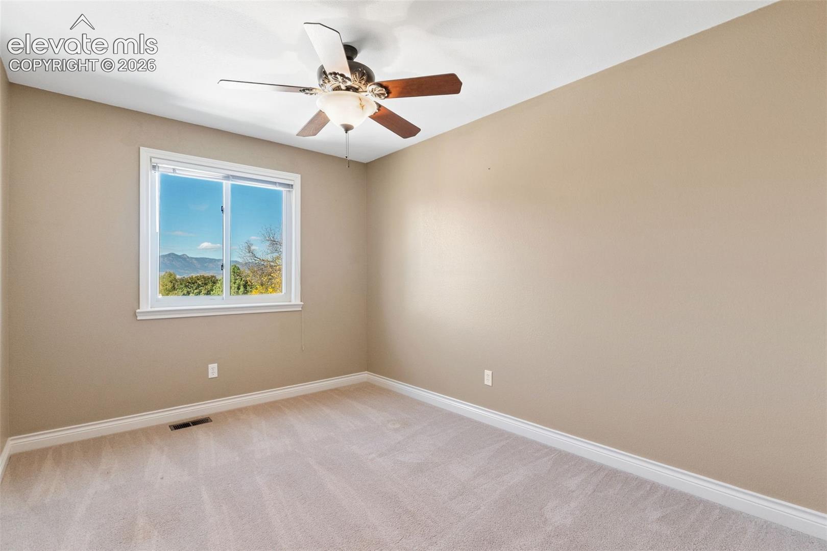 Room featuring neutral wall tones, wall-to-wall carpeting, a multi-blade ceiling fan with integrated lighting, and a single-hung window with mountain scenery