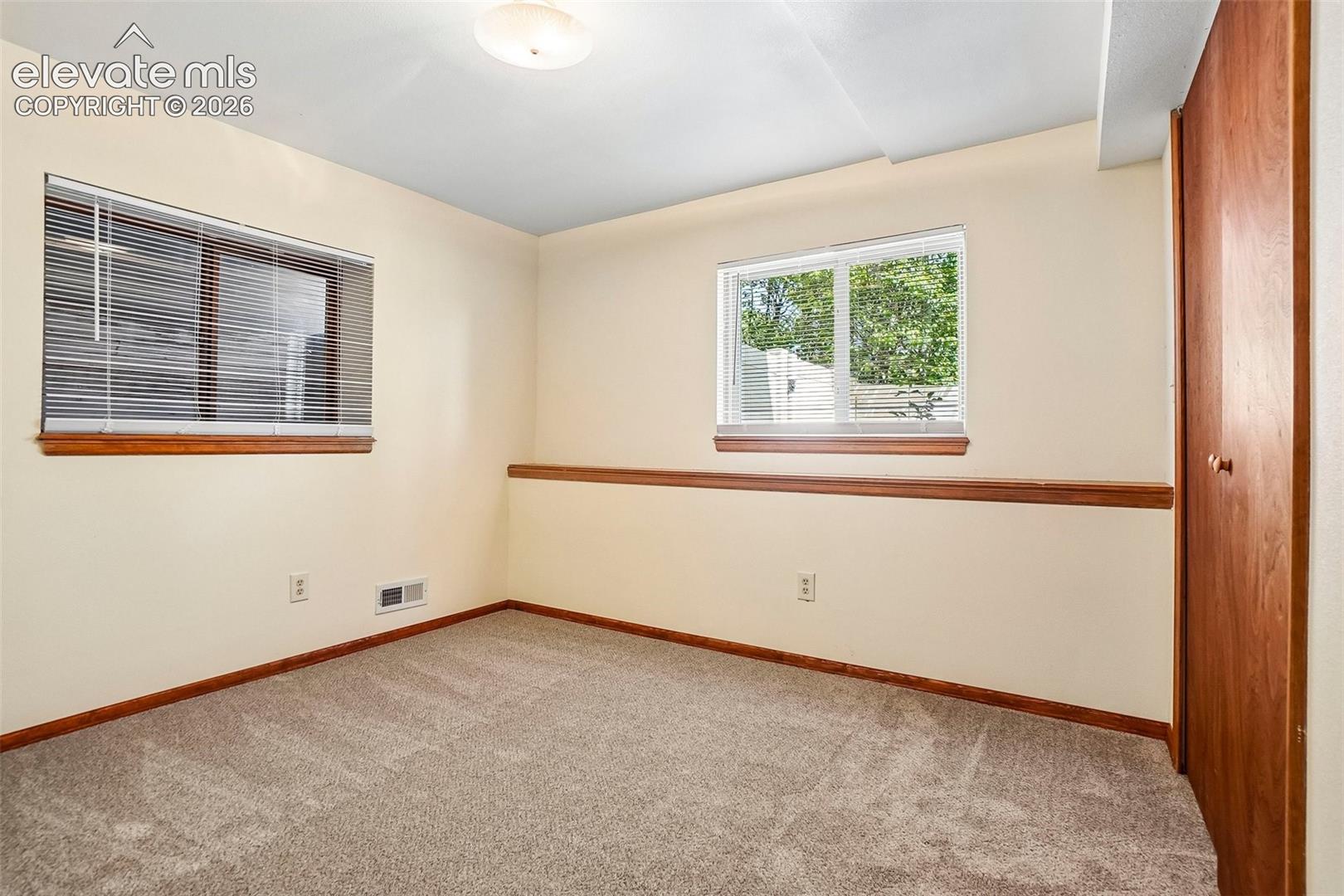 Guest bedroom in basement has garden-level window on one side.