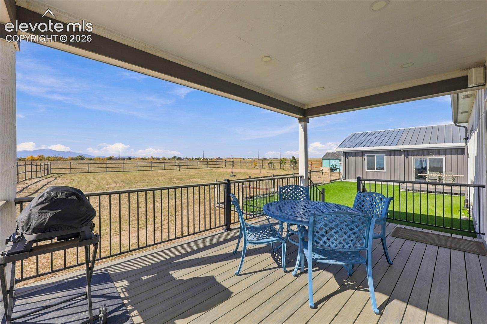 Covered composite deck featuring a metal railing, recessed ceiling lighting, and open terrain with a mountain backdrop