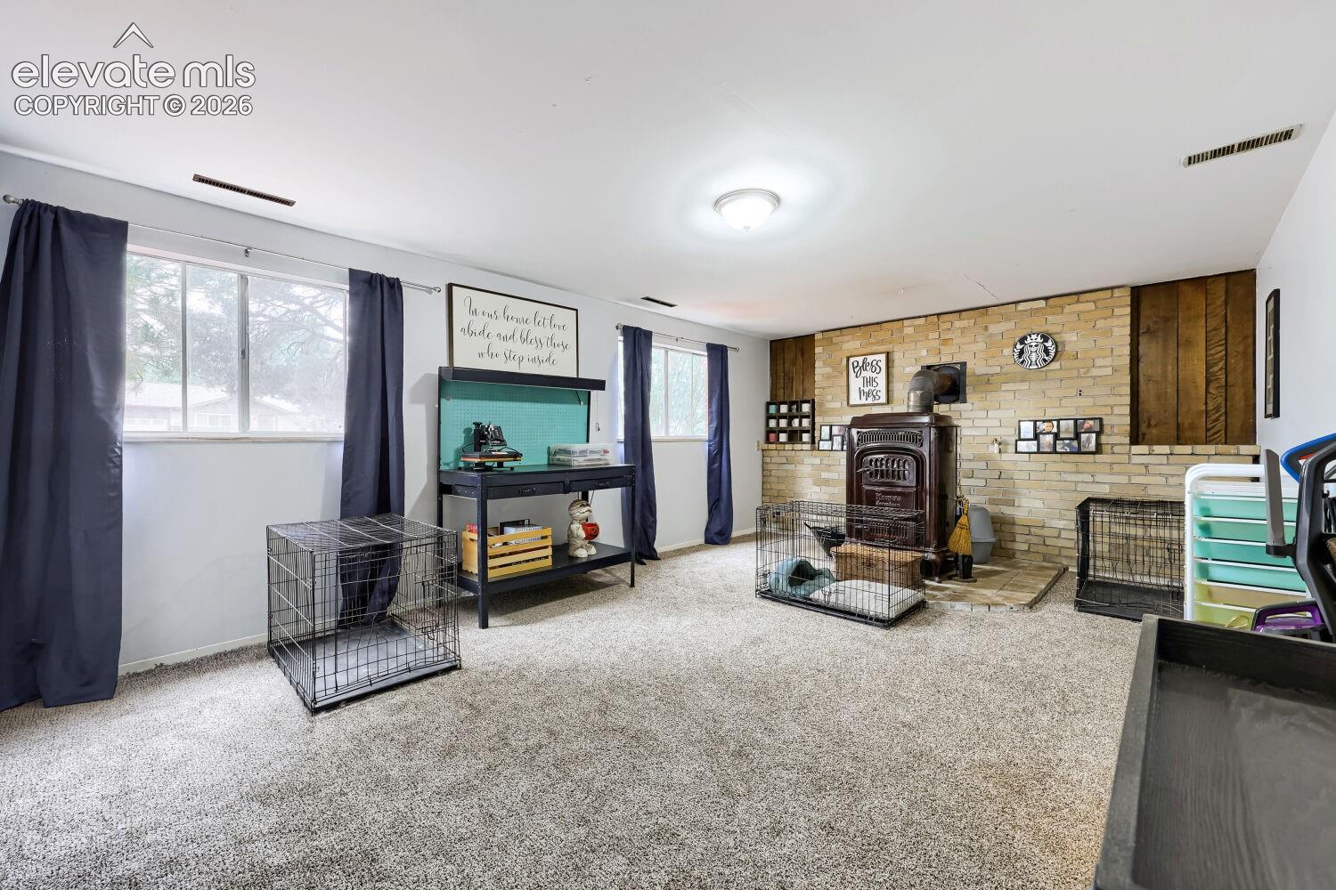 Carpeted flooring, multiple windows, brick accent wall, wood paneling, and a built-in stove
